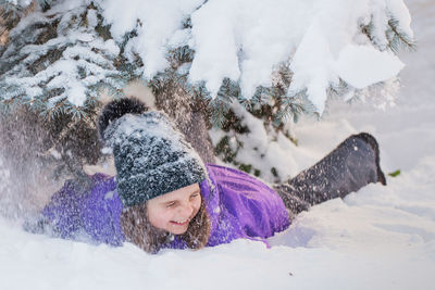 Girl playing on snow covered landscape during winter