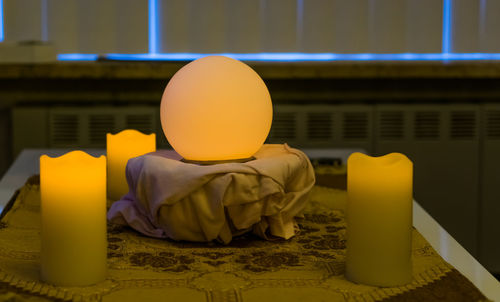 Close-up of yellow candles on table against building