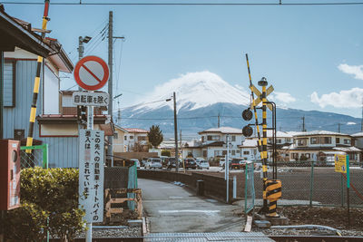 Road by buildings in city against sky