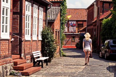 Rear view of woman walking on street by houses