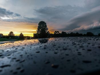 Surface level of wet land against sky during sunset