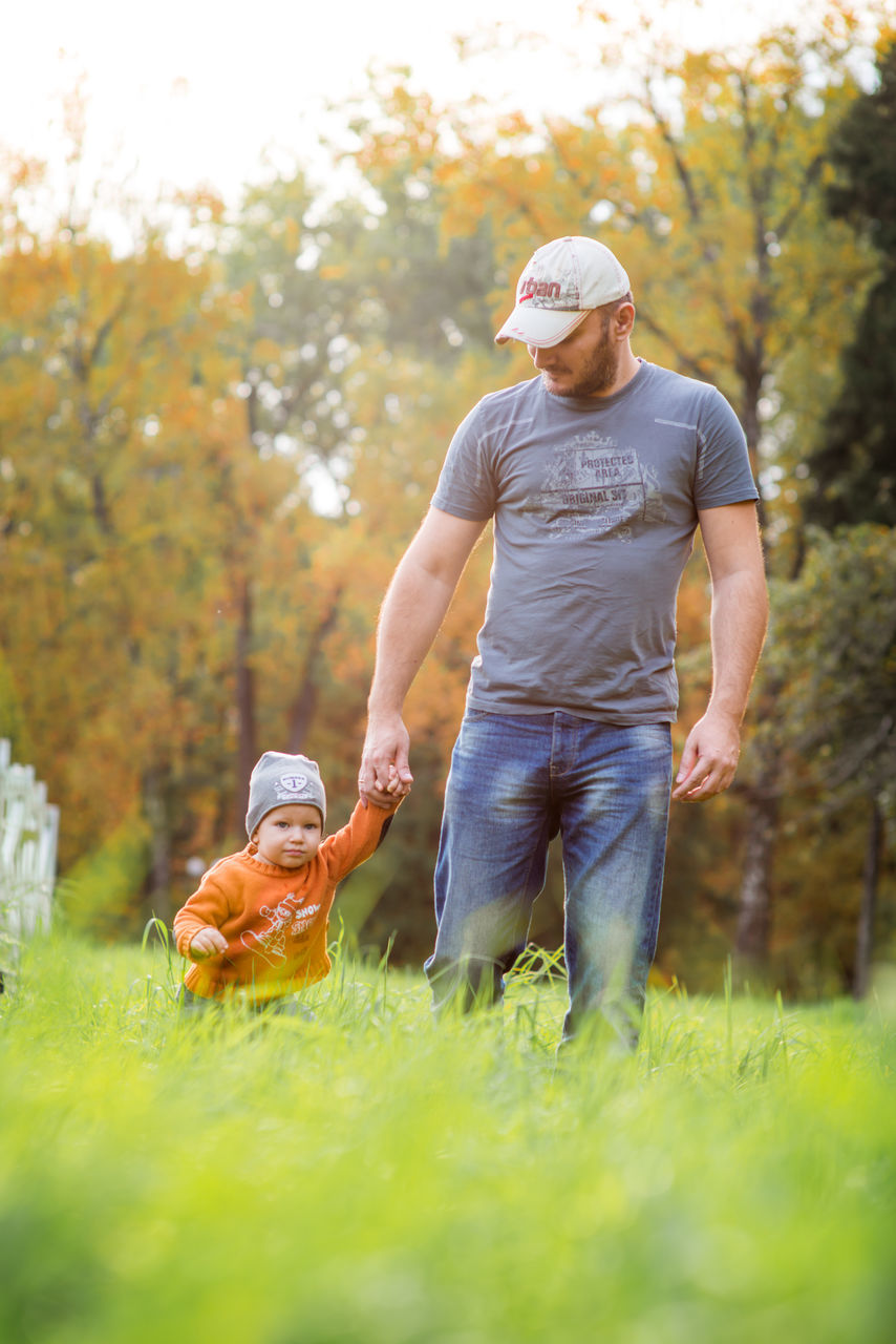 full length, casual clothing, lifestyles, leisure activity, rear view, selective focus, field, mature adult, day, young adult, person, surface level, toddler, solitude, color image