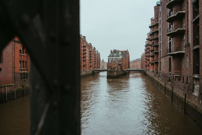 Canal amidst buildings in city against sky