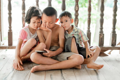 Siblings watching video over mobile phone while sitting on floor