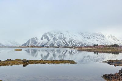 Scenic view of frozen lake by snowcapped mountains against sky