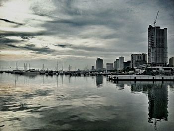 City at waterfront against cloudy sky