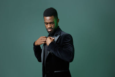 Portrait of young man standing against black background