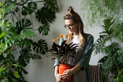 Young woman looking down while standing against plants