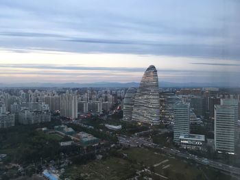 Aerial view of city at waterfront against cloudy sky