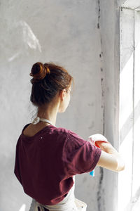 Rear view of woman standing by window