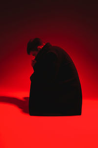 Side view of young man against red background