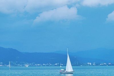 Sailboat sailing in sea against blue sky