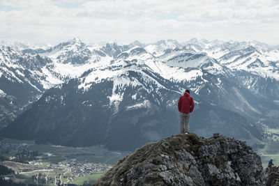 Rear view of man standing on cliff against european alps