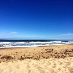 Scenic view of beach against clear blue sky