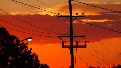 Low angle view of silhouette electricity pylon against sky during sunset