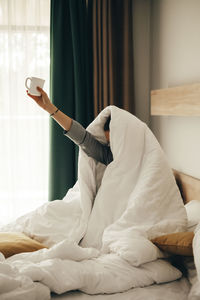 Midsection of man relaxing on bed at home