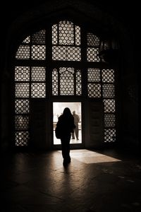 Rear view of silhouette woman walking towards doorway