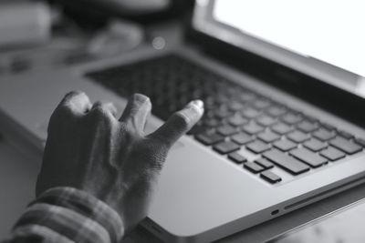 Cropped hand of person using laptop at desk