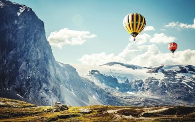 Hot air balloons flying over mountain against sky