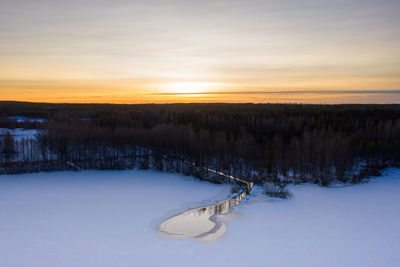 Scenic view of snow covered field against sky during sunset