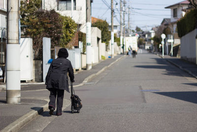 Rear view of man walking on road in city