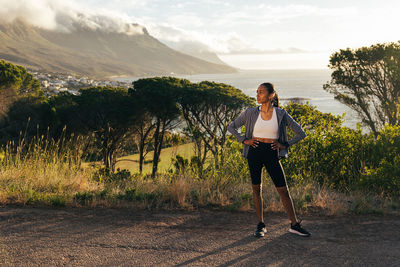 Full length of young woman standing against mountain