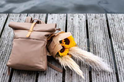 Traveler's backpack and a bunch of sunflowers lie on a pier.