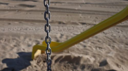 Close-up of swing hanging on sand