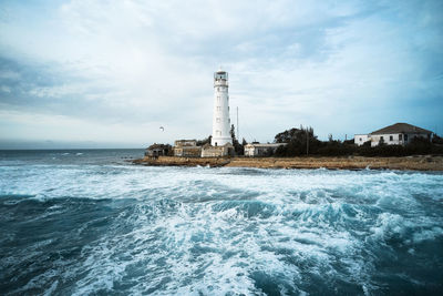 Lighthouse by sea against sky