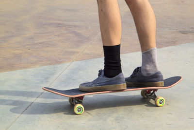 Low section of man skateboarding on footpath