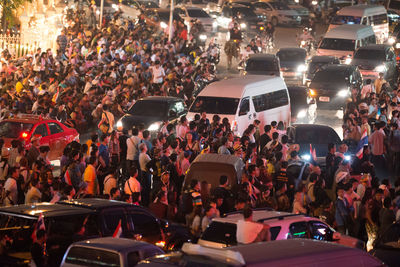 High angle view of crowd and vehicles on street in city