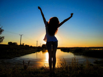 Rear view of boy standing in water at sunset