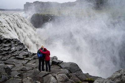 Couple looking at waterfall while standing on mountain