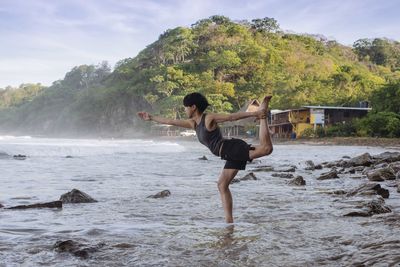 Side view of woman practicing yoga in river