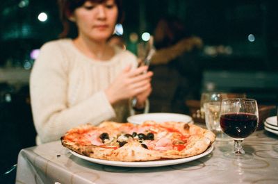 Woman eating pizza with wine at restaurant