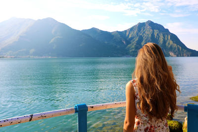 Rear view of woman looking at mountains against sky