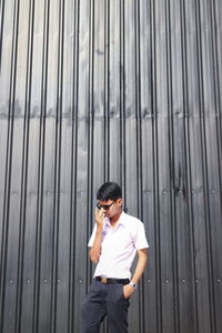 Young man standing against metal structure