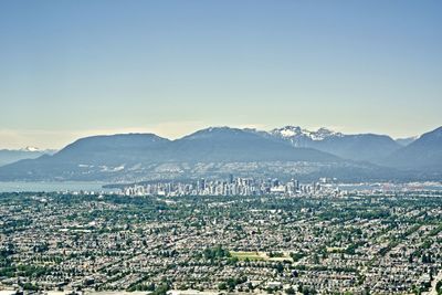 Aerial view of townscape and mountains against clear sky