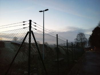 Fence on field against sky at sunset