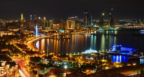 Illuminated buildings by river at night