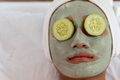 Close-up of woman with facial mask lying at spa