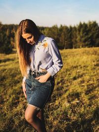 Young woman standing on field against sky