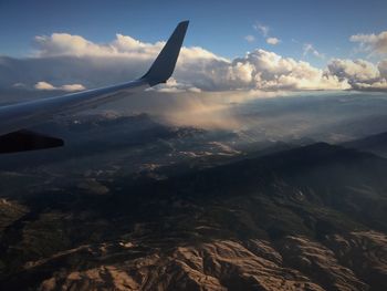 Aerial view of airplane wing over landscape against sky