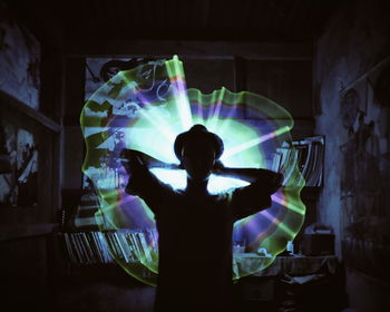 Rear view of silhouette boy standing against illuminated lights