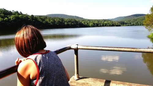 Rear view of woman looking at lake against sky