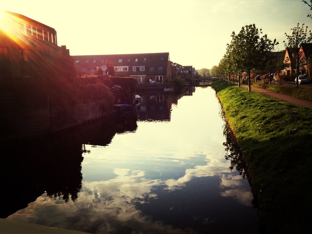 CANAL AMIDST BUILDINGS AGAINST SKY DURING SUNSET