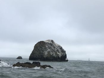 Rock formation in sea against sky