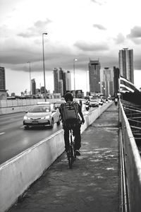 Rear view of man riding bicycle on street in city