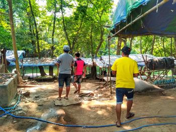 Rear view of people standing by trees