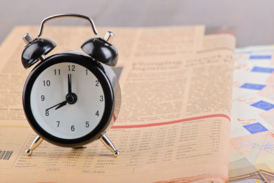 Close-up of alarm clock and newspaper